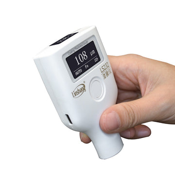 A hand holding the LS232 paint thickness meter, demonstrating its ergonomic size and portability.